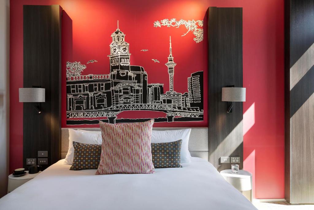 a bedroom with a large bed with a red wall at Mercure Auckland Queen Street in Auckland