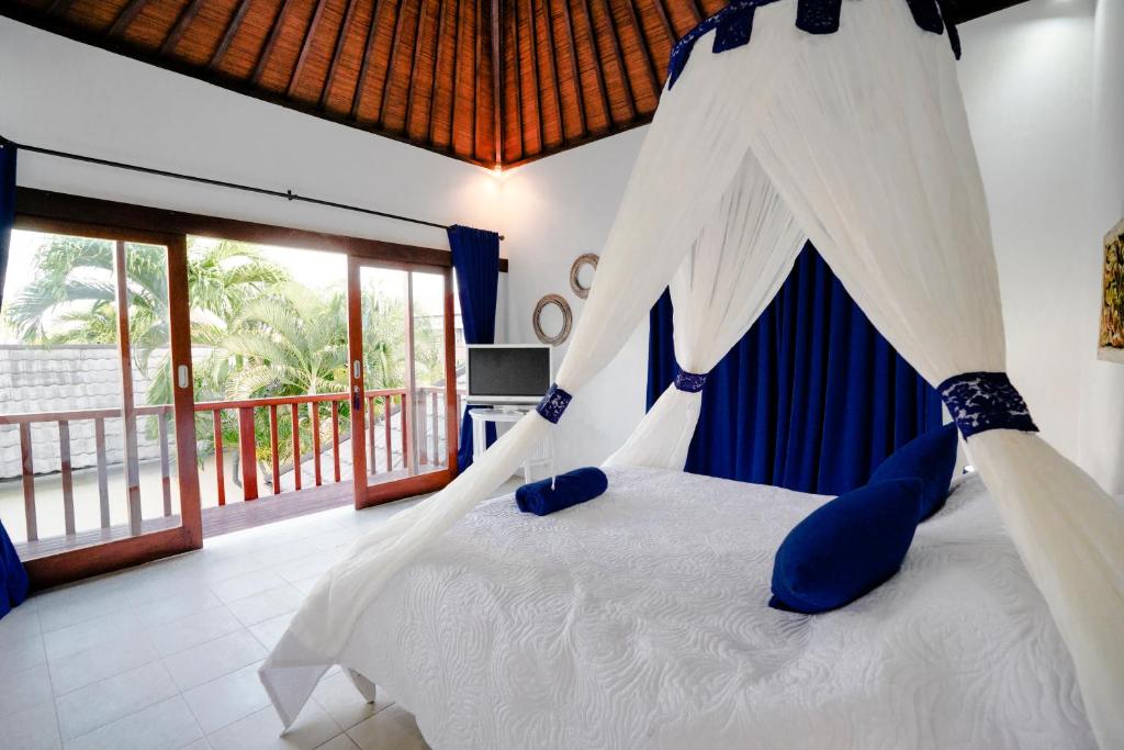 a bedroom with a bed with a canopy and a balcony at Villa Dewi in Seminyak