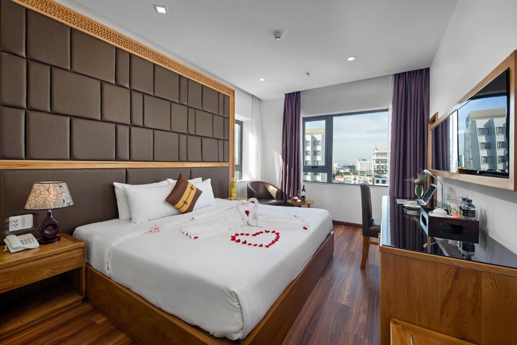a hotel room with a large bed and a window at Bliss Luxury Hotel & Spa in Da Nang