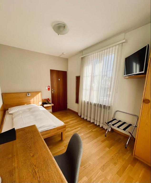 a bedroom with a bed and a table and a tv at Hotel Rössli in Basel