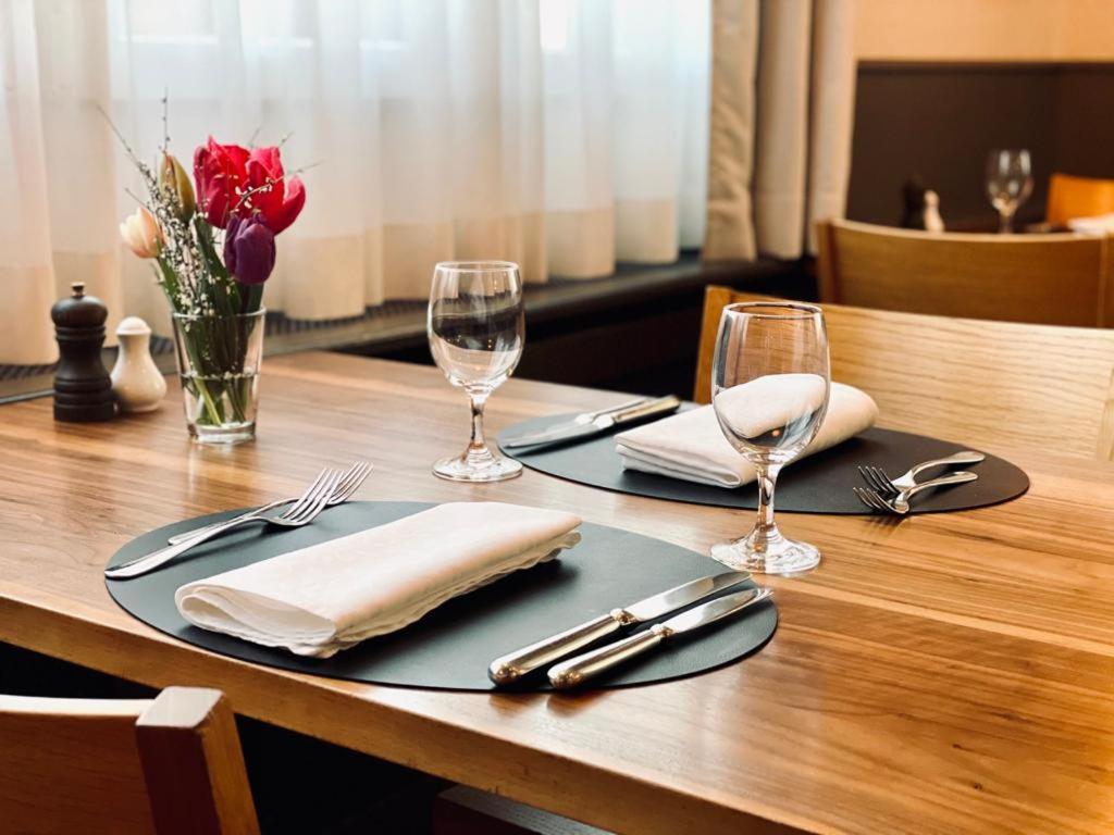 a wooden table with two plates and wine glasses at Hotel Rössli in Basel