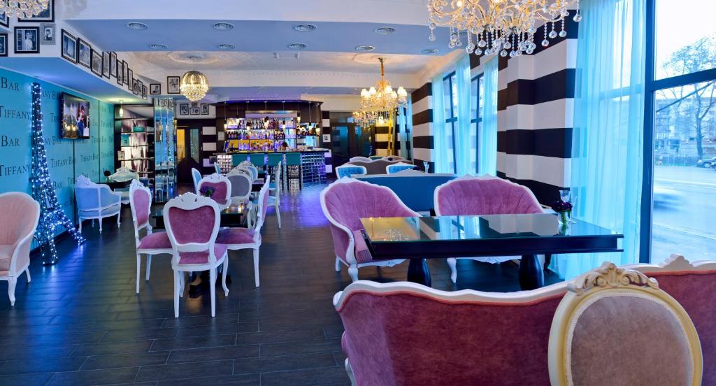 a restaurant with pink chairs and tables in a room at River Side Hotel Tbilisi in Tbilisi City