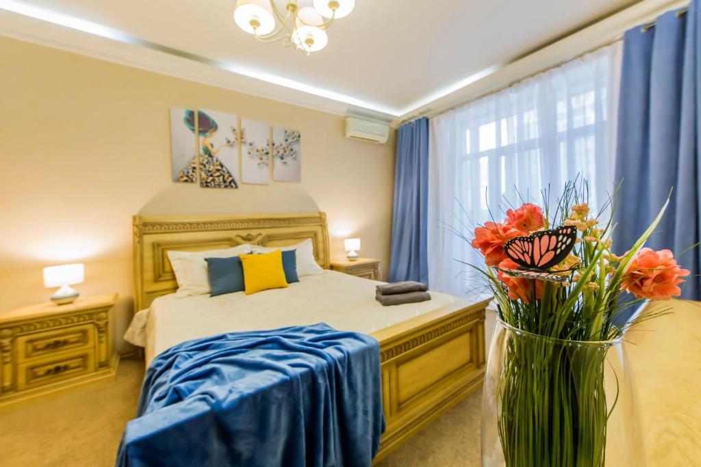 a bedroom with a bed and a vase with flowers in it at 2к квартира на Басейній, ТРЦ Гуллівер in Kyiv