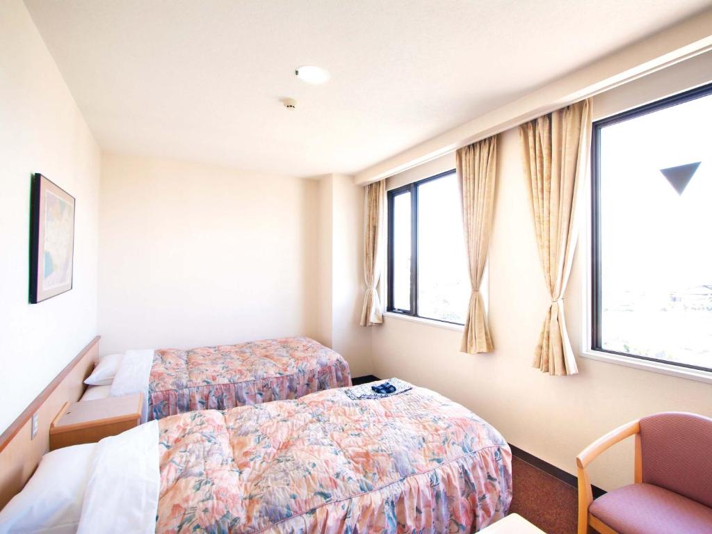 a hotel room with two beds and a chair at Hotel Daikokuya in Yatsushiro
