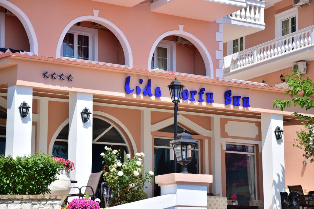 Lido Corfu Sun Hotel 4 Stars All-inclusive في بينيتسيس: مبنى وردي مع علامة تشير إلى أن لا فيرونيكا سار