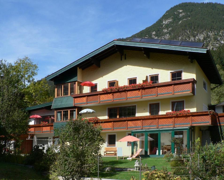 a large building with red umbrellas and a mountain at Antares am See in Maurach