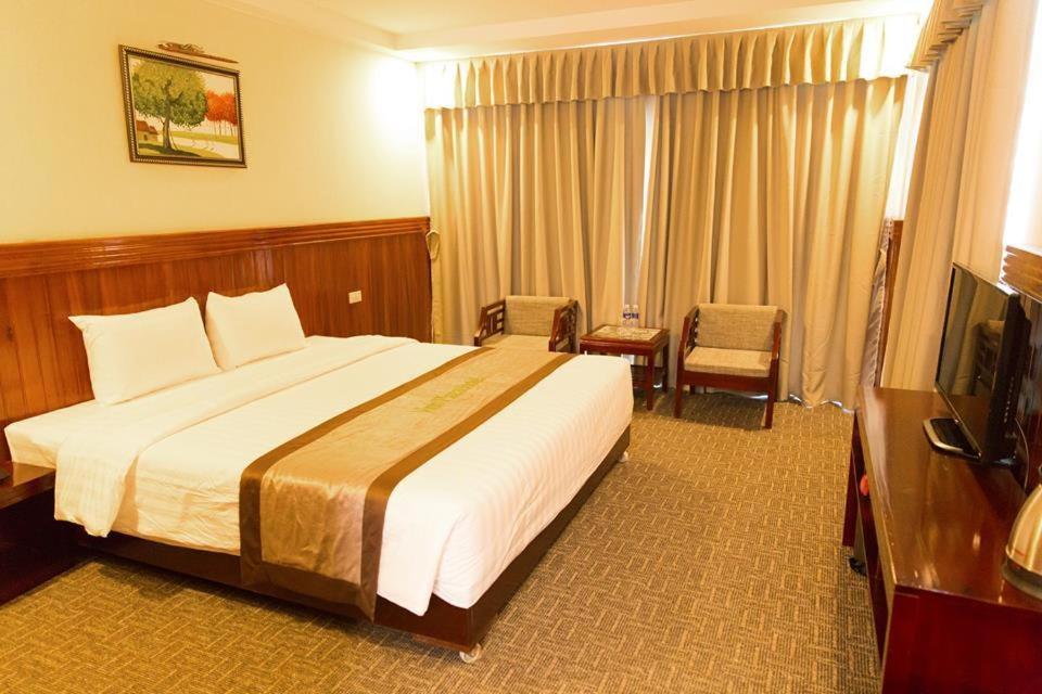 Una habitación de hotel con una cama grande y un televisor. en Vinh Plaza Hotel, en Vinh