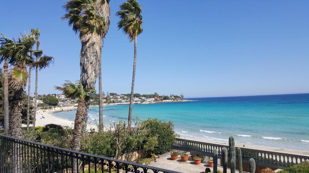 een uitzicht op een strand met palmbomen en de oceaan bij Villa Sogno sulla Spiaggia in Fontane Bianche