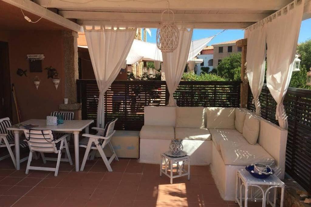 eine Terrasse mit einem Sofa, einem Tisch, einem Tisch und Stühlen in der Unterkunft Bilocale ristrutturato con piscina. Spiagge vicine. in Porto Rotondo
