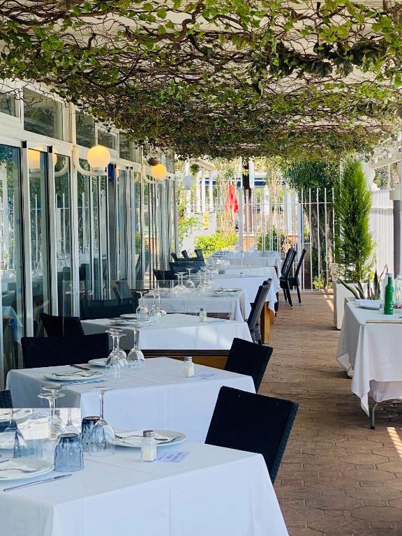 a restaurant with white tables and chairs and windows at Hotel Playa Canet in Canet de Berenguer