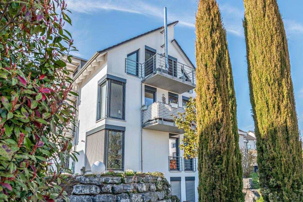 ein weißes Haus mit Bäumen davor in der Unterkunft Ferienwohnung mit Gartenblick in Überlingen