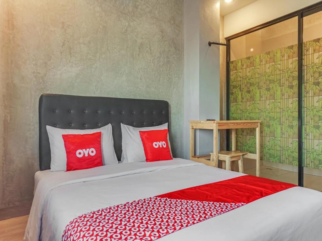 1 dormitorio con 1 cama grande con almohadas rojas en OYO 90305 De Umbrela Mansion Syari'ah Ciputat, en Tangerang