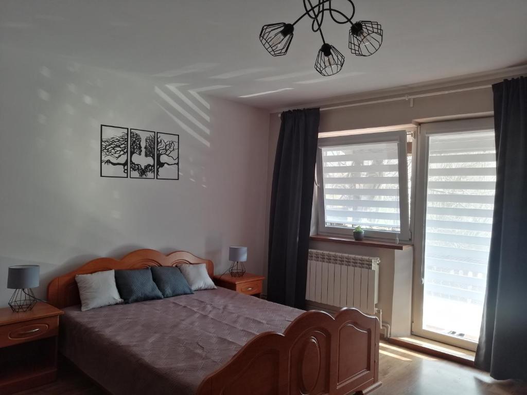 a bedroom with a bed and two windows at Mieszkanie Nad Popradem INPIW03 in Piwniczna-Zdrój