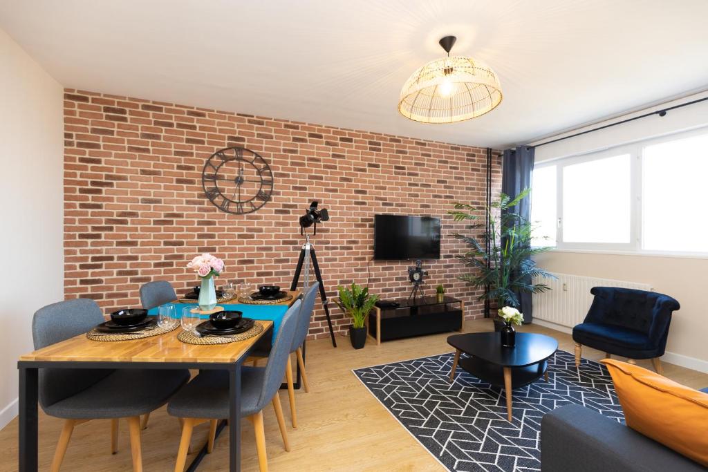 een woonkamer met een tafel en een bakstenen muur bij Le petit Manhattan - Appartement privé de 45 m2 - 2 à 4 personnes - Parking privé in Metz