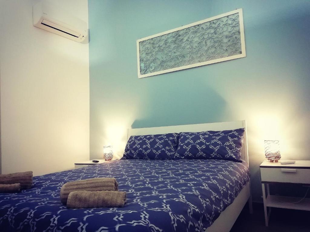 een slaapkamer met een bed en een blauwe muur bij Theatron Houses- Centro Storico in Catania
