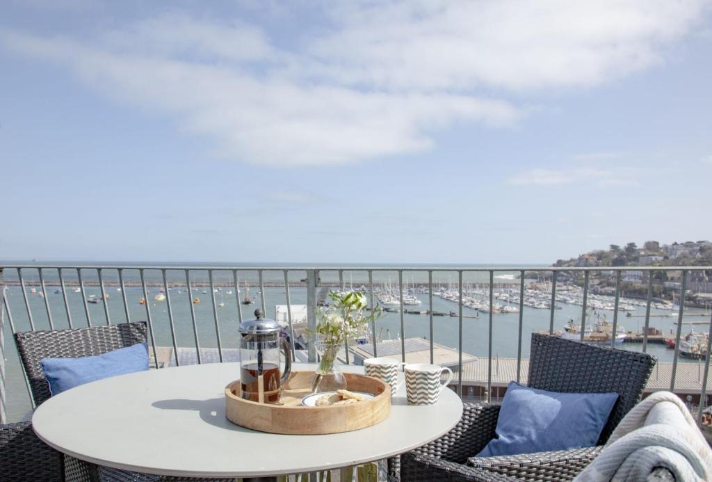 a table on a balcony with a view of the water at Cliff Cottage, Brixham in Brixham