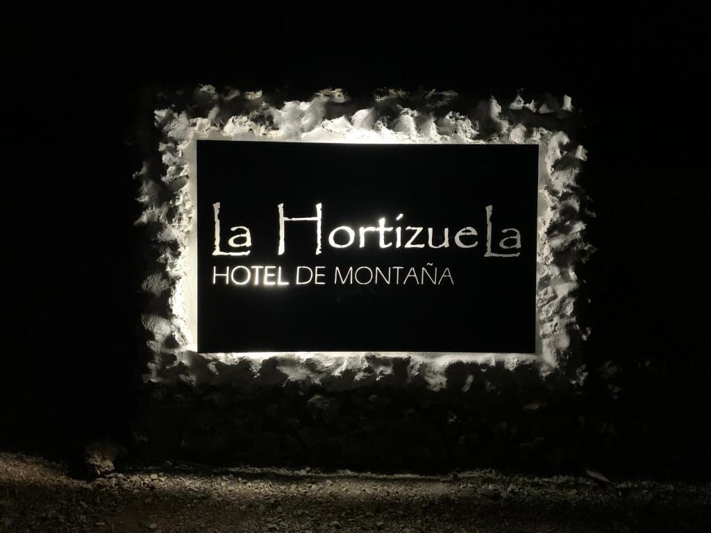 a sign for a hotel de montréal at night at Hotel de Montaña La Hortizuela in Coto Ríos