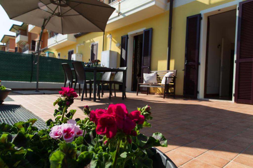 a patio with flowers and a table with an umbrella at Sweet Home a Vallefoglia by Yohome in Montecchio