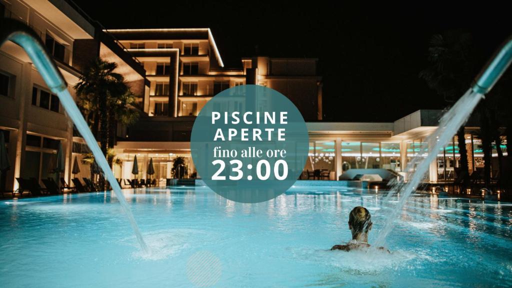 a person in a swimming pool with a sign in the water at Hotel Terme Venezia in Abano Terme