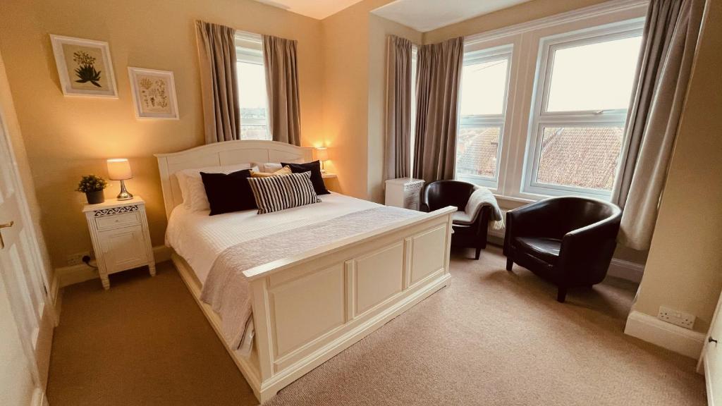 una camera con un letto bianco e due sedie di Arbour House B&B a Swanage