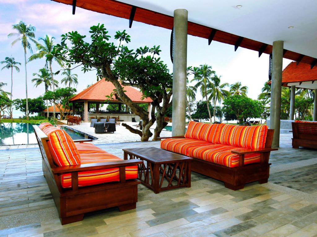 an outdoor patio with an orange couch and a table at Hikka Tranz by Cinnamon in Hikkaduwa