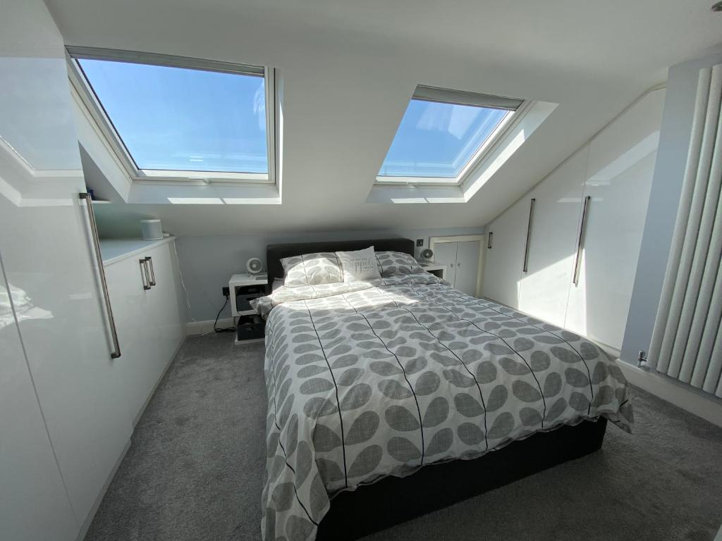 a bedroom with a bed with two skylights at 3 bed Apartment in Colliers Wood in London