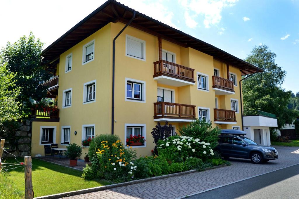 a yellow apartment building with a car parked in front at Appartement Lisa Schweiger in Kirchberg in Tirol