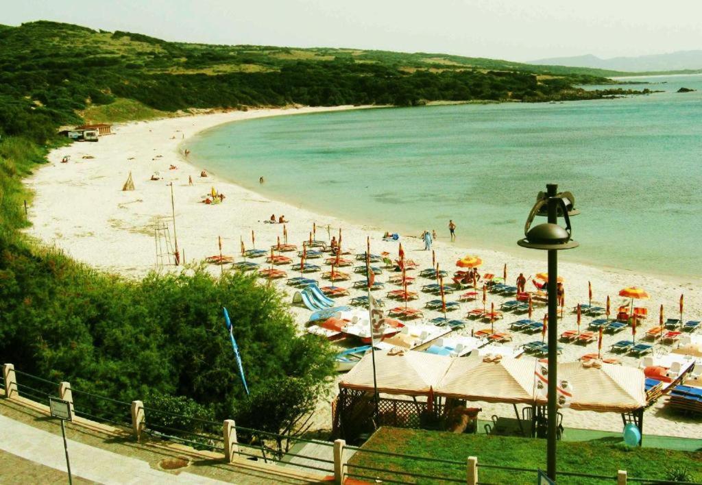 una spiaggia con molti ombrelloni e persone in acqua di Borgo Spiaggia Isola Rossa a Isola Rossa