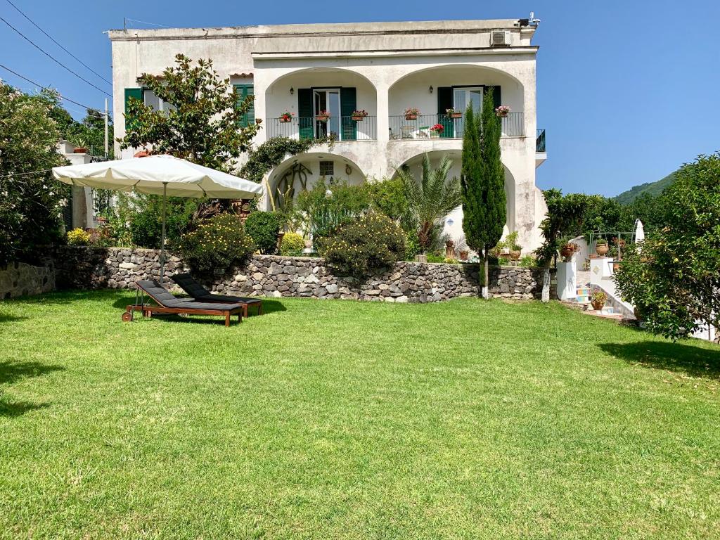 een huis met een gazon met een bank en een paraplu bij Villa Vincenzo Di Meglio in Ischia
