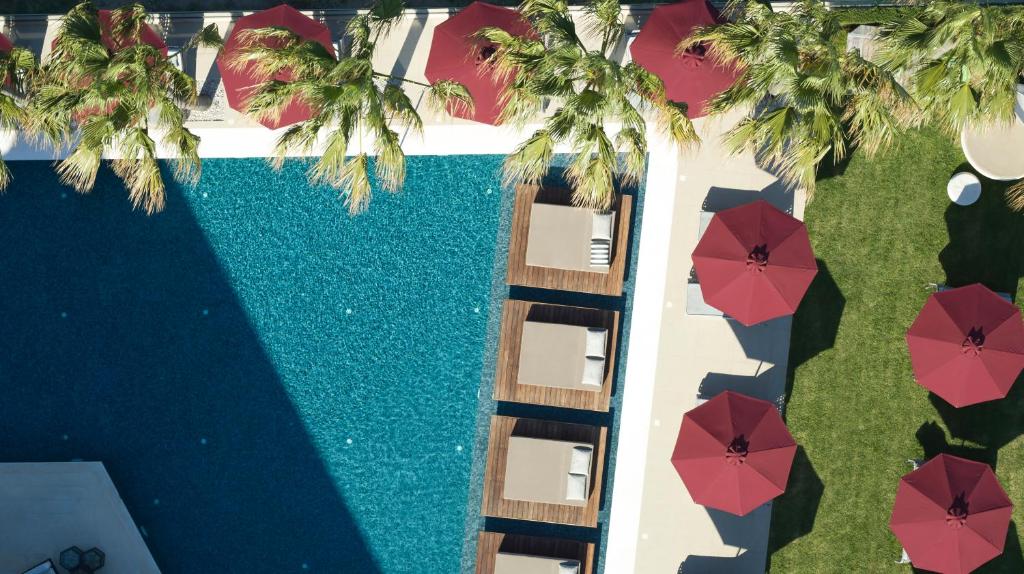 an overhead view of a swimming pool with red umbrellas at Aqua Blu Boutique Hotel & Spa, Adults Only- Small Luxury Hotels of the World in Kos Town