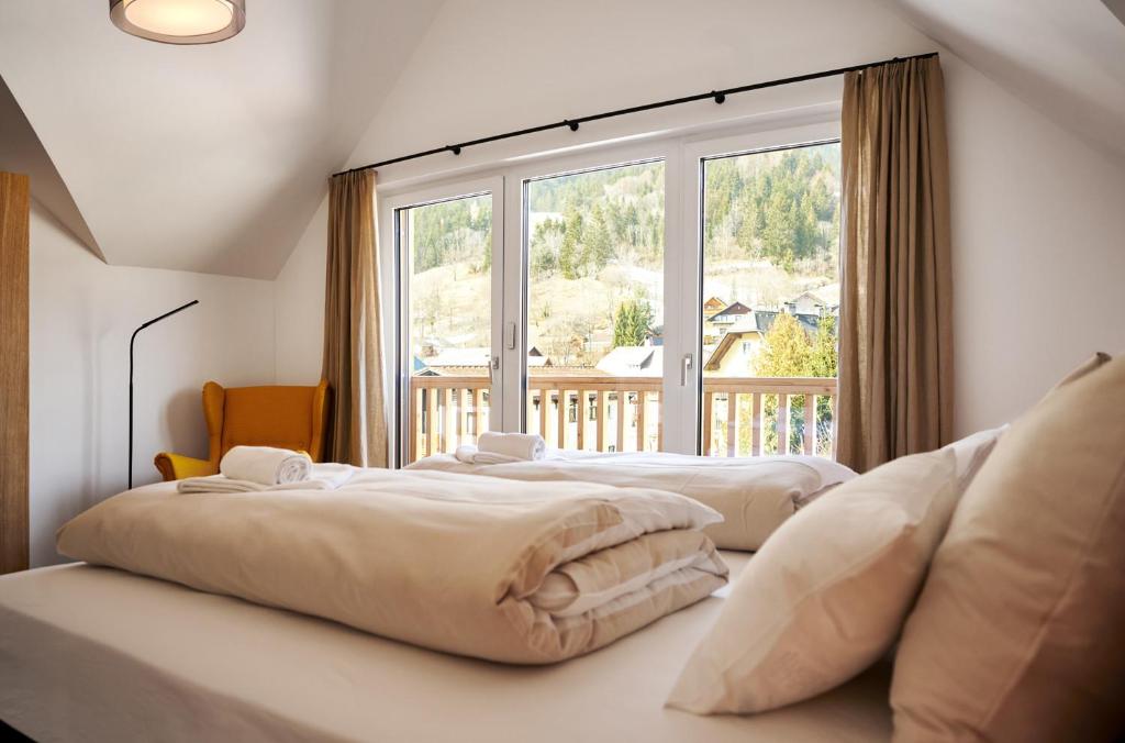two beds in a room with a large window at die Tauplitz Lodges - Alm Lodge A13 by AA Holiday Homes in Tauplitz