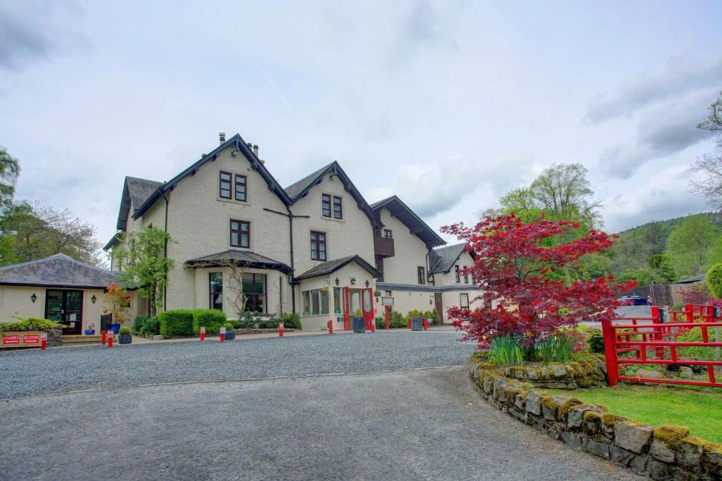 uma grande casa branca com uma cerca vermelha em Philipburn Hotel, BW Signature Collection em Selkirk