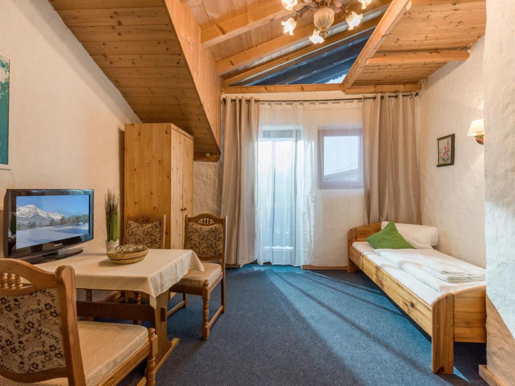 a living room with a couch and a table and a tv at Pension Konrad in Söll