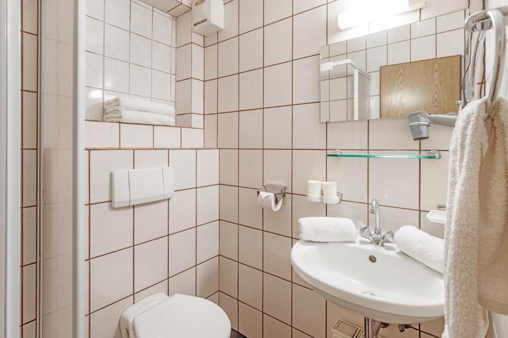 a white bathroom with a sink and a toilet at Pension Konrad in Söll
