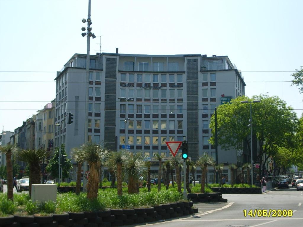 a large building with palm trees in front of a street at Domo Hotel Mondial in Düsseldorf