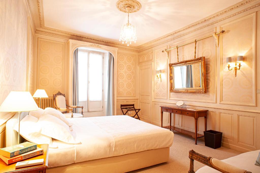 a bedroom with a bed and a table and a mirror at Les Cordeliers in Sarlat-la-Canéda