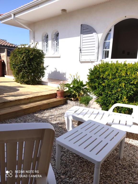 two white benches sitting in front of a house at GITE JARDIN/TERRASSE COSY PRES PLAGES in Arès