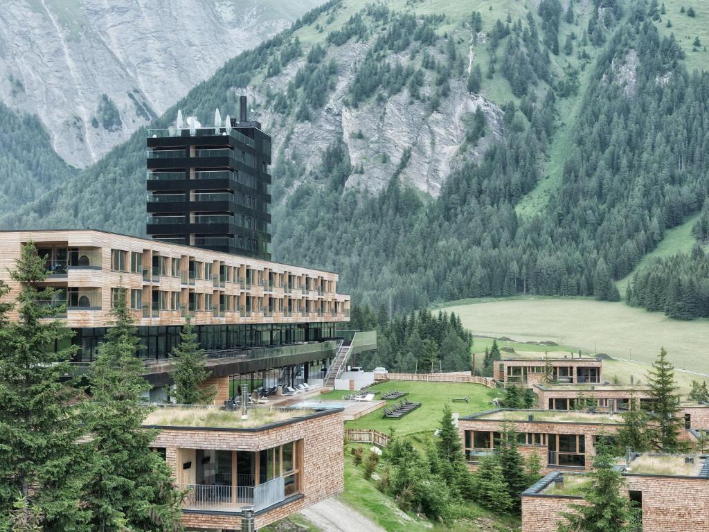 un bâtiment en face d'une montagne arborée dans l'établissement Gradonna Mountain Resort Chalets & Hotel, à Kals am Großglockner