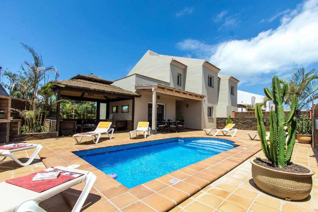 a backyard with a swimming pool and a house at Villa privada en Corralejo in Corralejo
