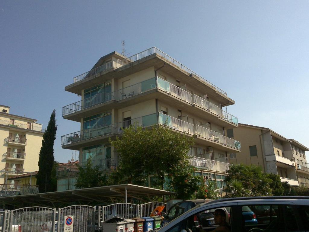 un edificio alto con coches estacionados frente a él en Hotel Elvira, en Rímini