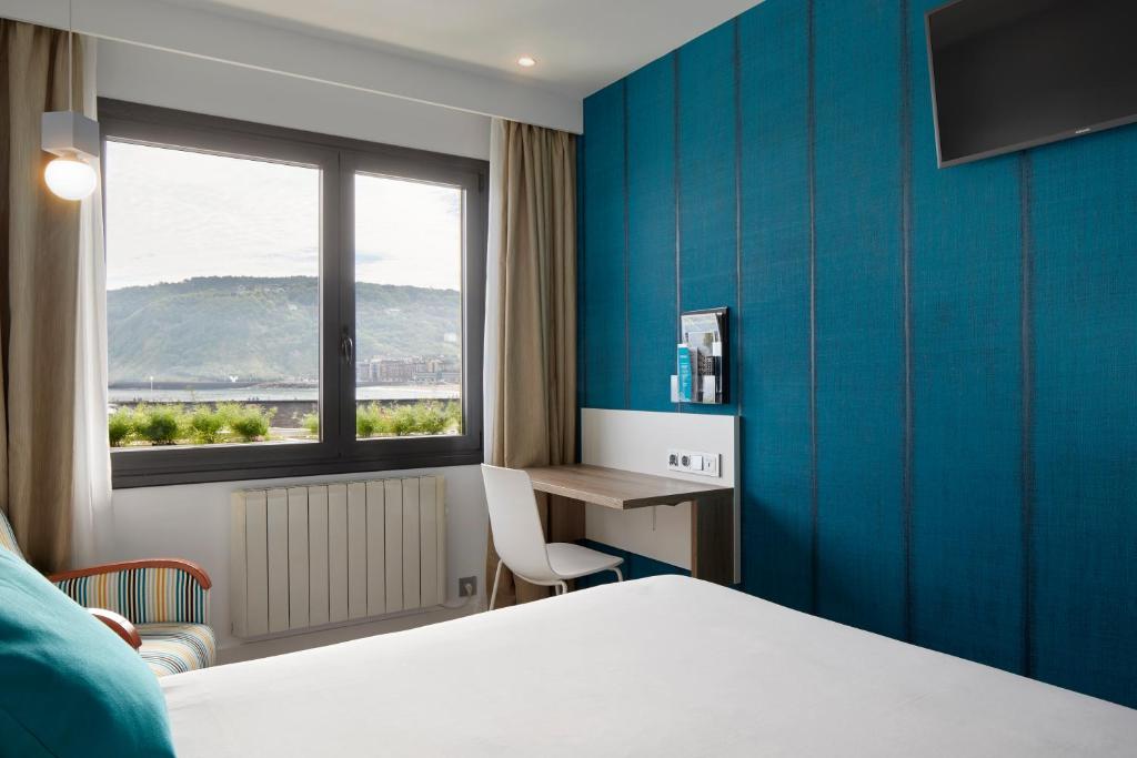 a hotel room with a bed and a desk and a window at Hotel Parma in San Sebastián