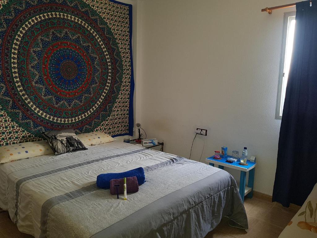 um quarto com uma cama com uma grande tapeçaria na parede em laurainu em Puerto del Rosario