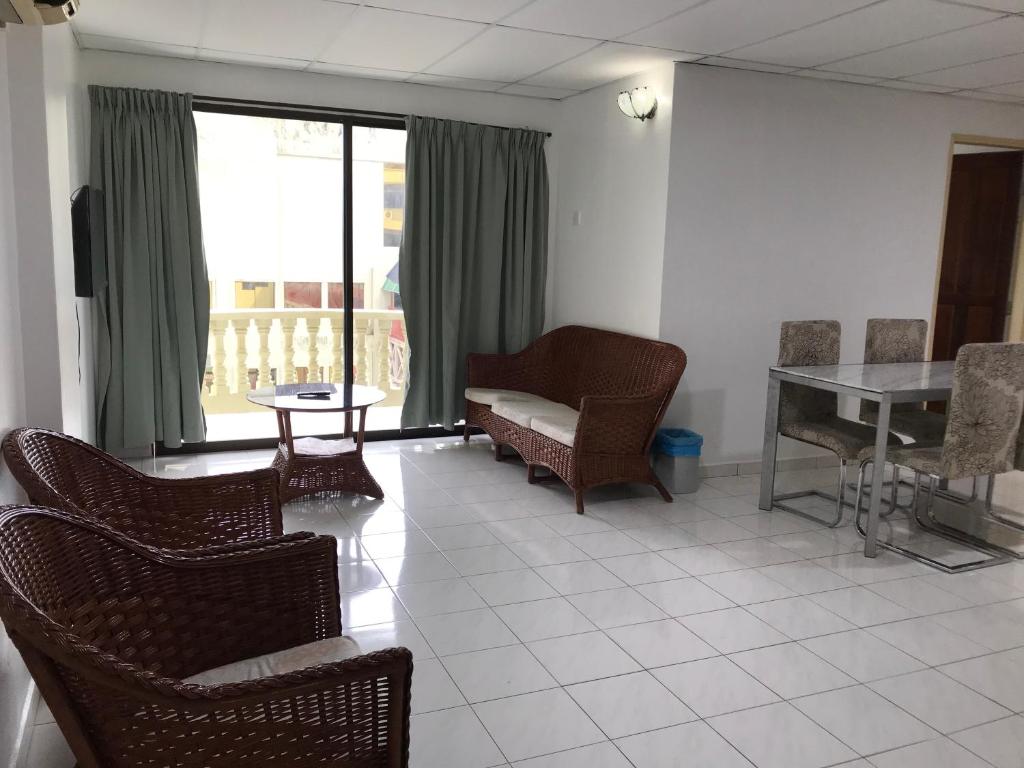 ein Wohnzimmer mit Stühlen, einem Tisch und einem Fenster in der Unterkunft Pangkor Coralbay Resort 201 apartment in Pulau Pangkor