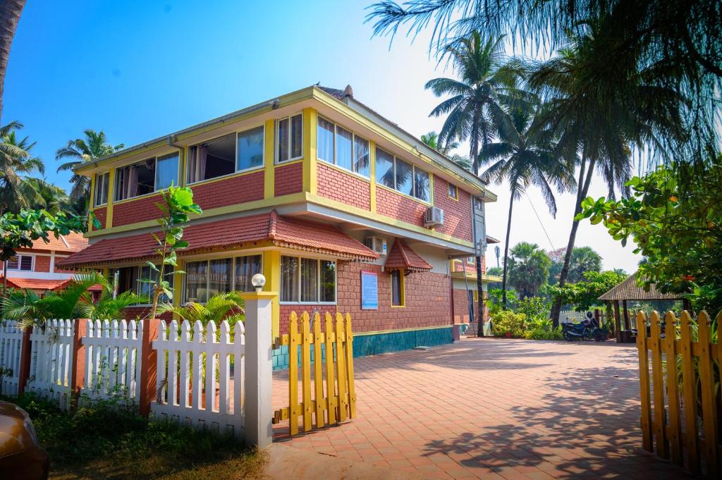 a house with a white fence in front of it at Glucklich Beach Cottages in Kundapur