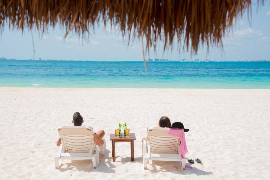 eine Gruppe von Menschen, die am Strand auf Stühlen sitzen in der Unterkunft Privilege Aluxes Adults Only in Isla Mujeres