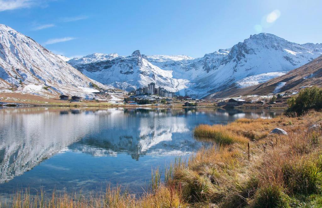 un lac avec des montagnes enneigées en arrière-plan dans l'établissement Les Suites – Maison Bouvier, à Tignes