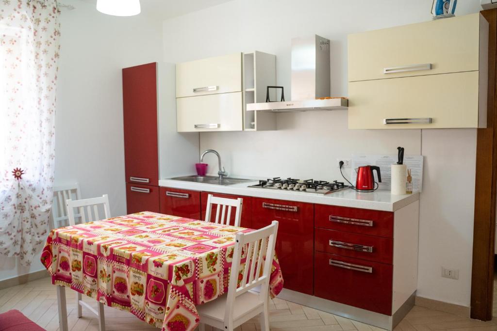 a kitchen with red cabinets and a table with a tablecloth at Appartamenti DeSi in Tropea