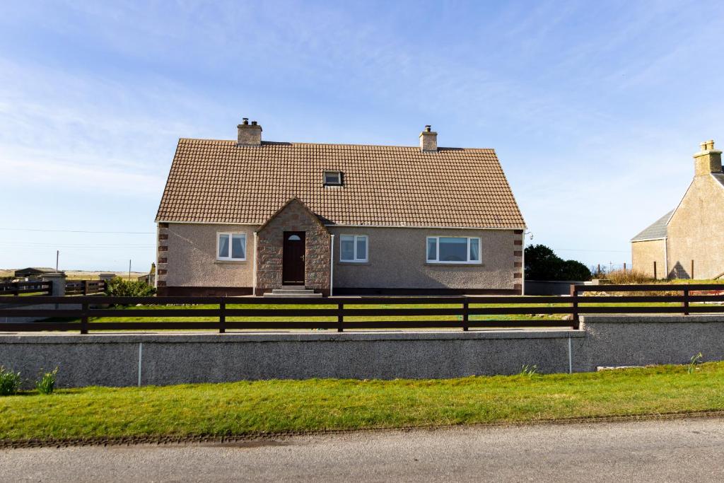 uma casa com uma cerca em frente em Ar Dachaigh, North Uist em Paible