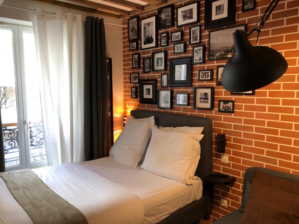 - une chambre dotée d'un mur en briques avec un lit et une lampe dans l'établissement Résidence Labyrinthe, à Paris