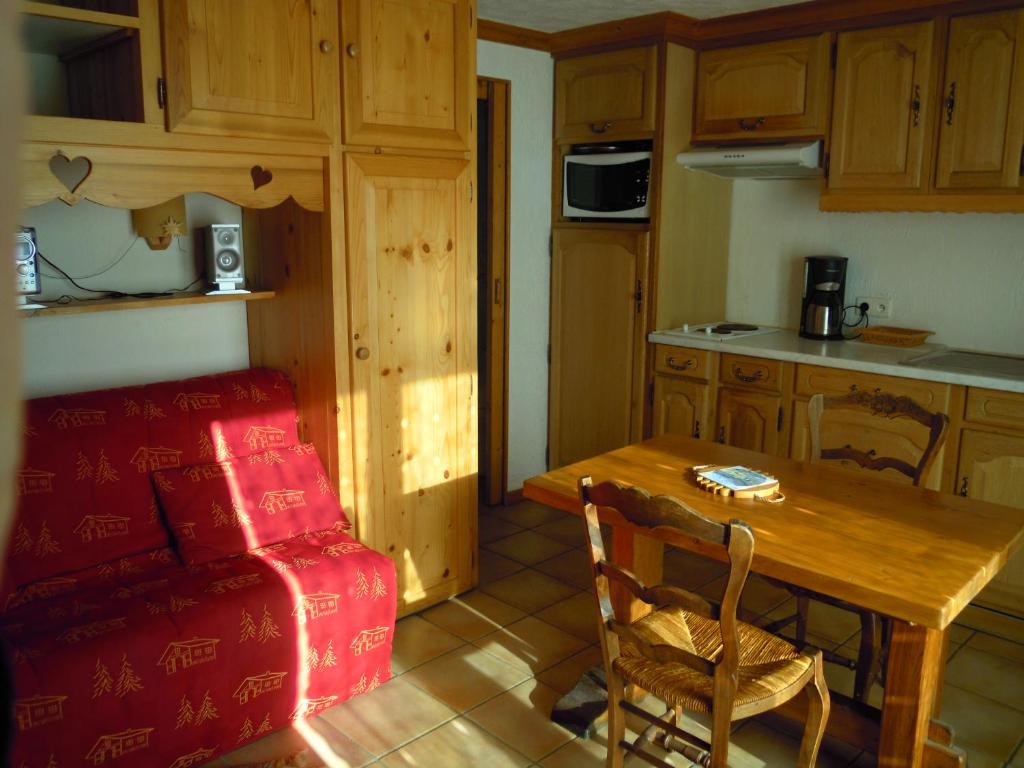 a kitchen with a wooden table and a red couch at A4 km de Megève très joli studio avec jacuzzi ,vue sur les montagnes au calme in Praz-sur-Arly